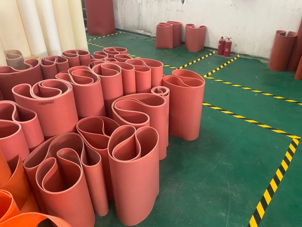 Red fabric-reinforced silicone conveyor belts made to order at the JAWLON factory, each marked with its size